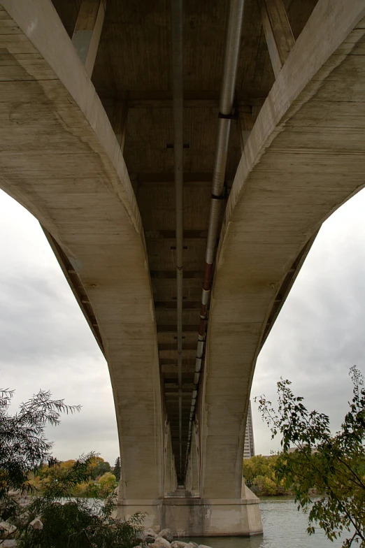 view from the bottom up under a bridge with a cloudy sky