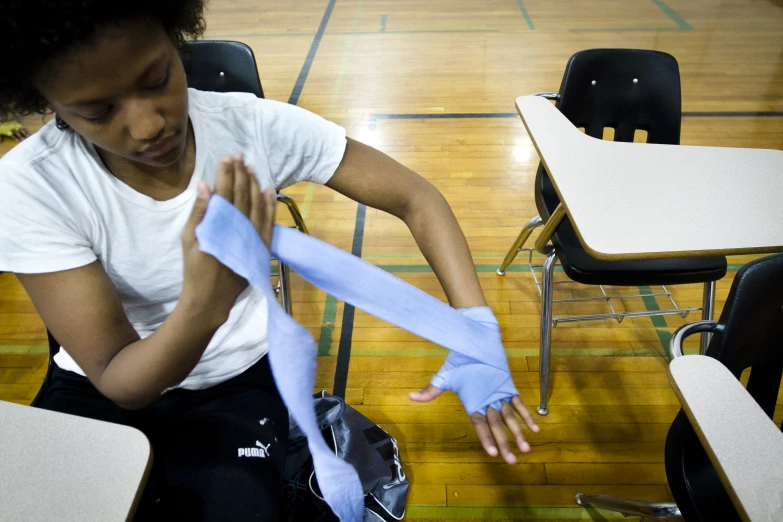 a girl at school tying a blue bow for a school chair