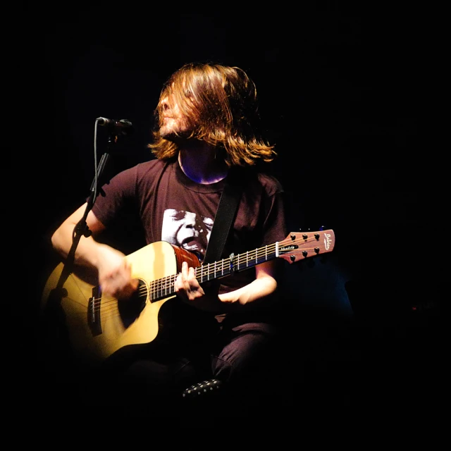 a man sitting on the floor with a guitar