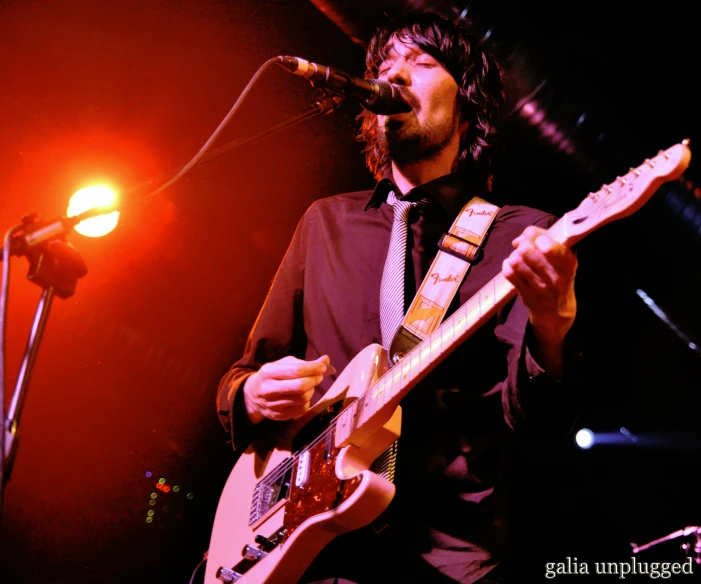 a man holding a guitar while standing next to microphone