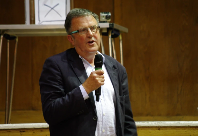 a man speaking into microphone in front of speaker's