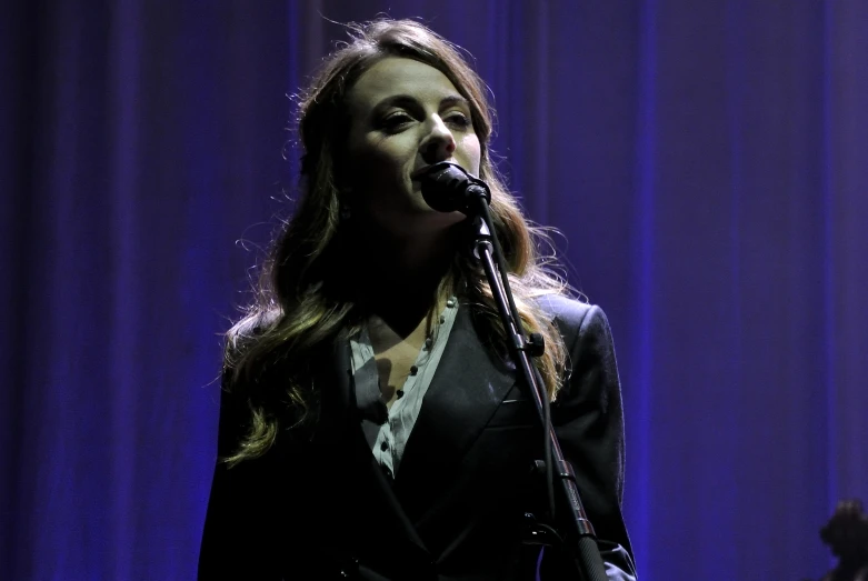 a woman in black jacket and tie holding a microphone