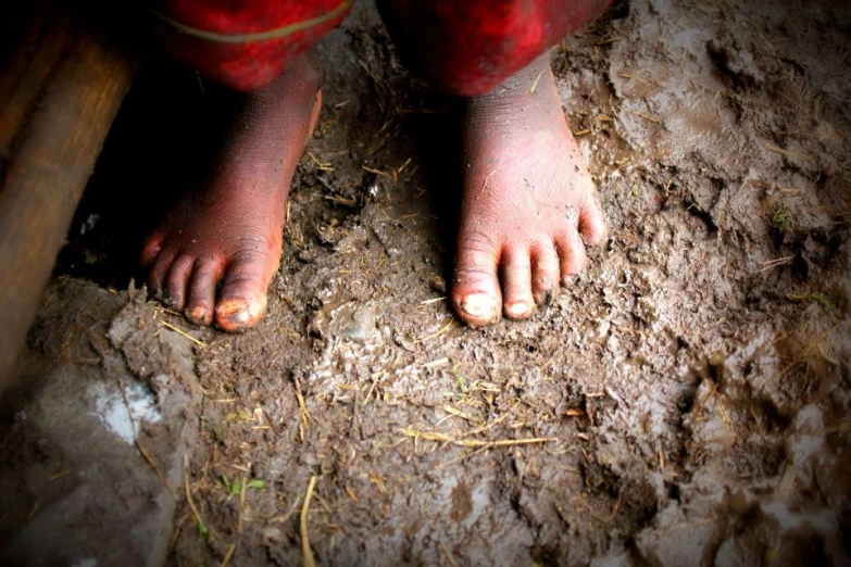 a barefooted child standing on dirt with bare feet