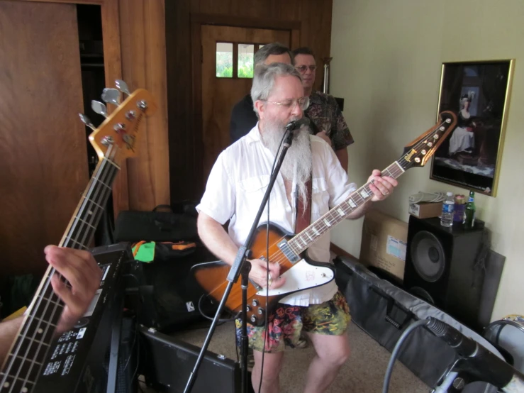 a man playing guitar in a room with other musicians