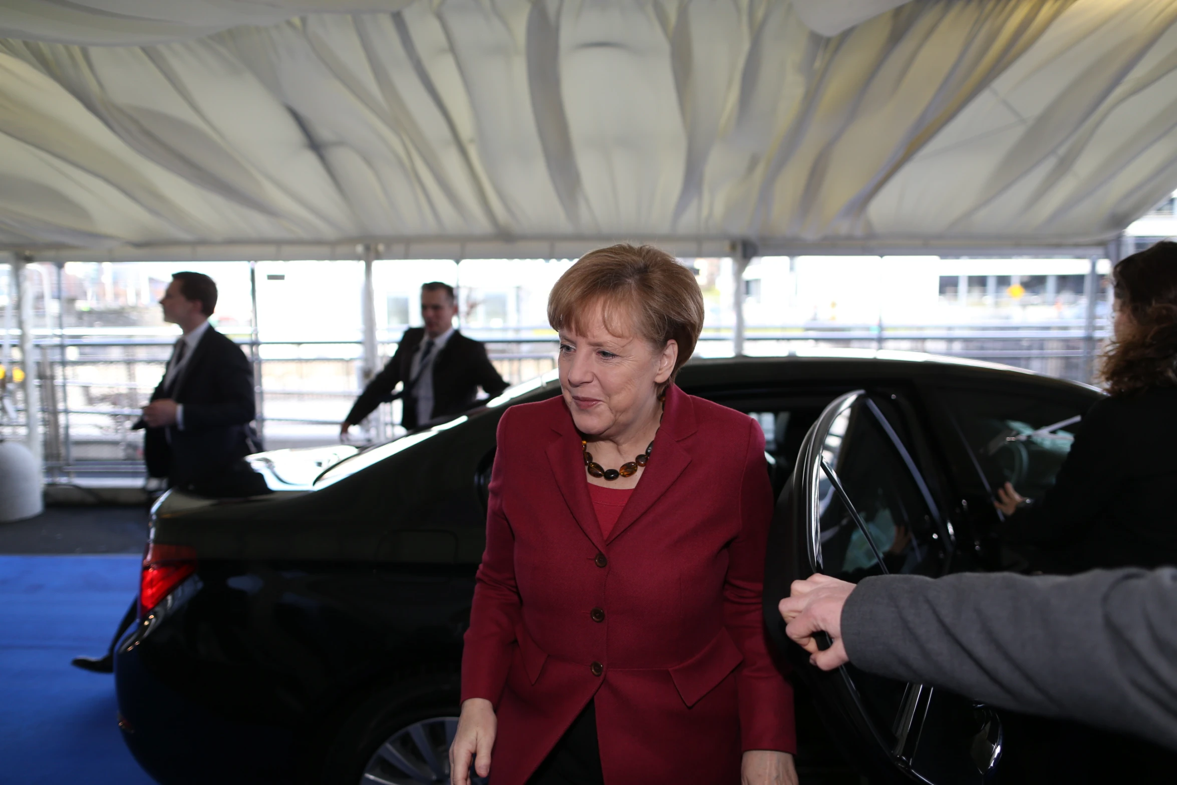 an image of a woman in red standing next to a car