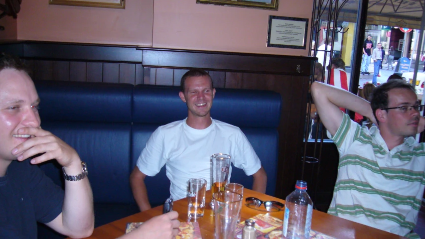 three men sitting at a table and having drinks