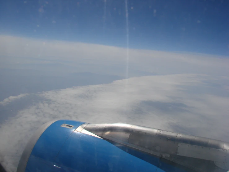 looking out an airplane window at a wing under a cloud