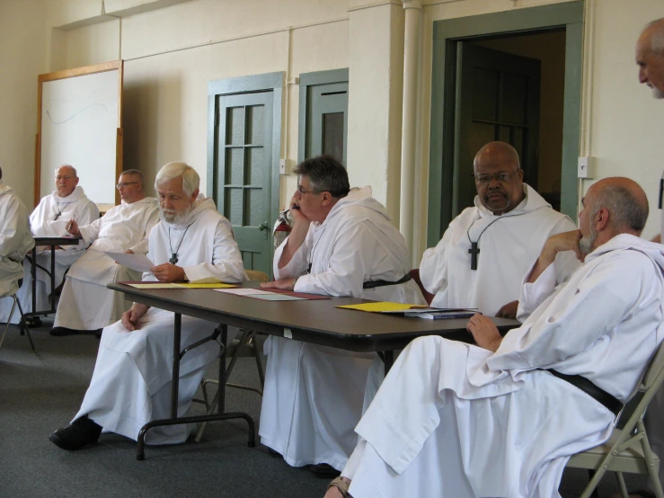 a group of people in robes sitting at a table