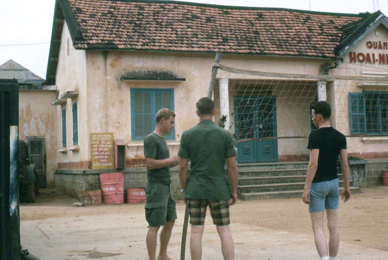 three men standing outside of a building talking