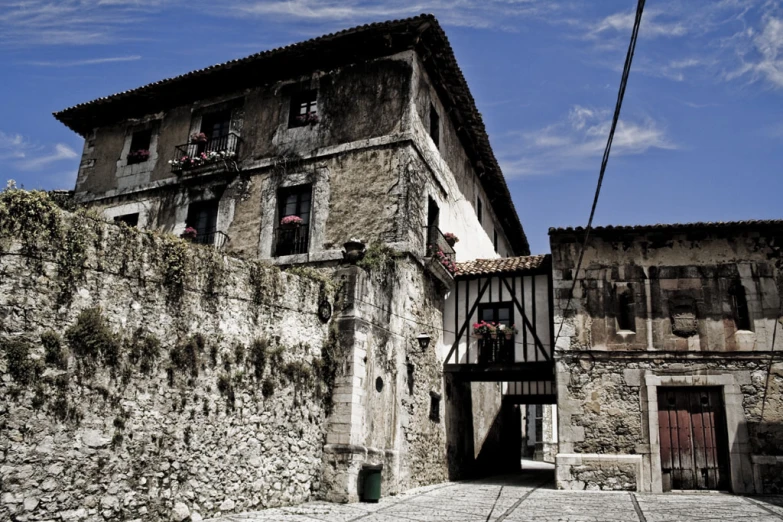 this is a old stone wall that separates an alley with a house