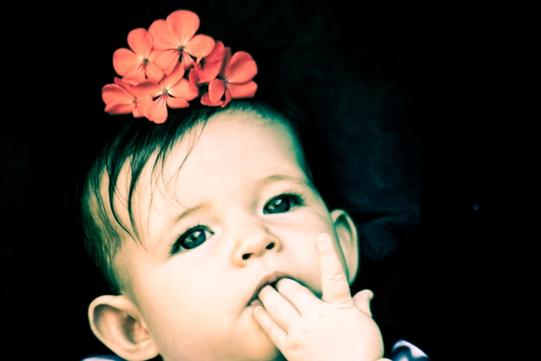 a baby girl with a red flower on her head and nails