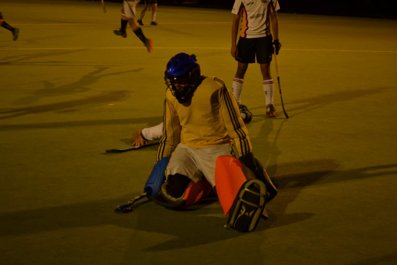 two men with stick's are sitting down on the field