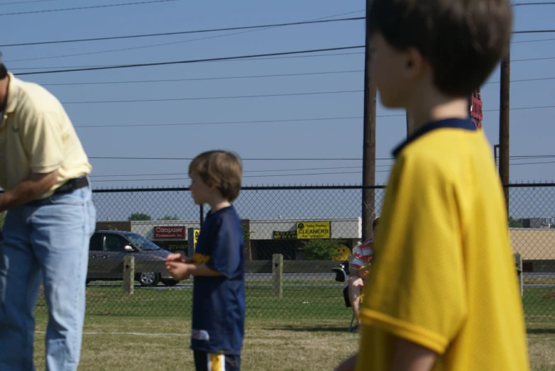 the boy is holding a bat with his hands and watching as another boy holds his hand out to him