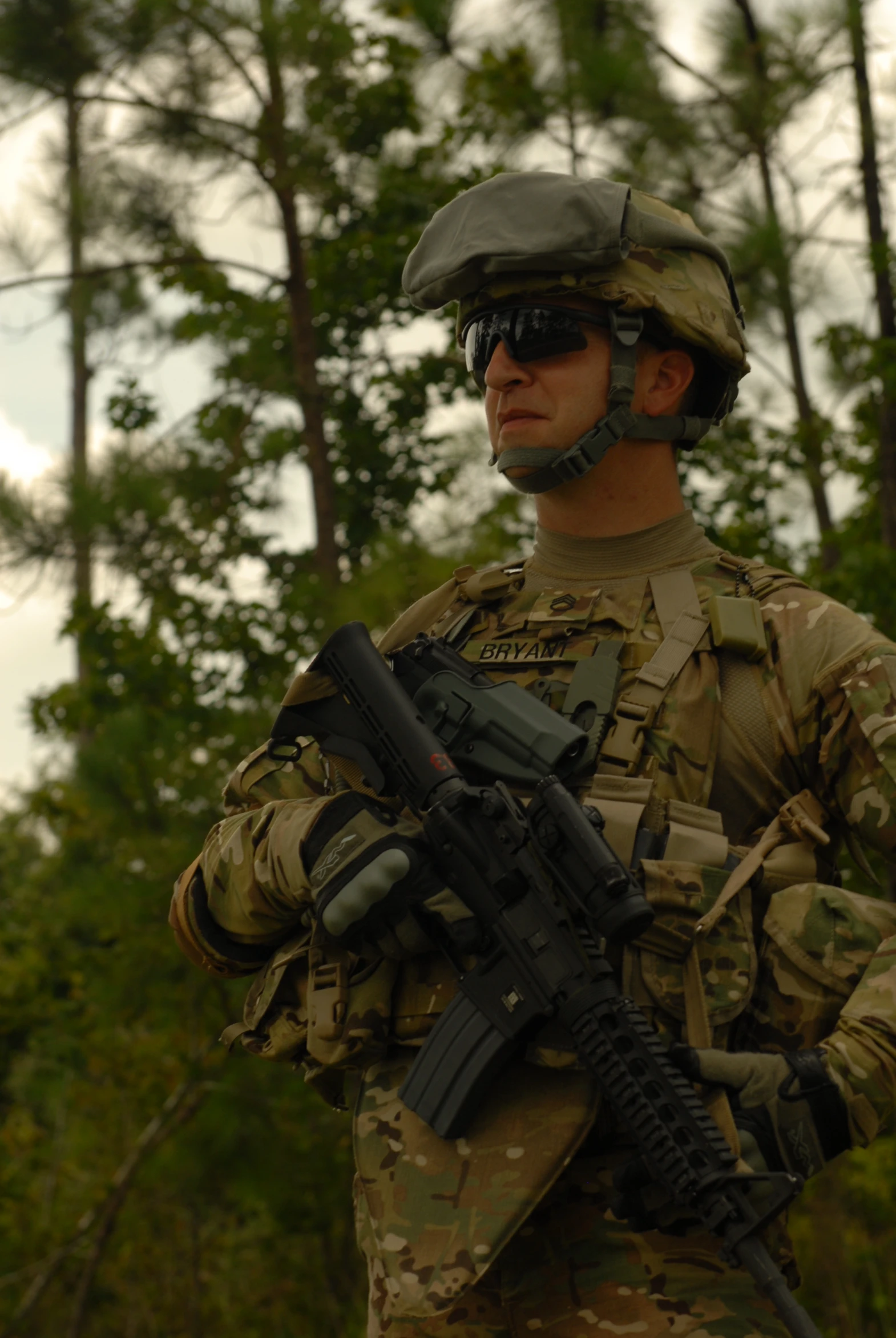 a soldier holds his rifle near a tree