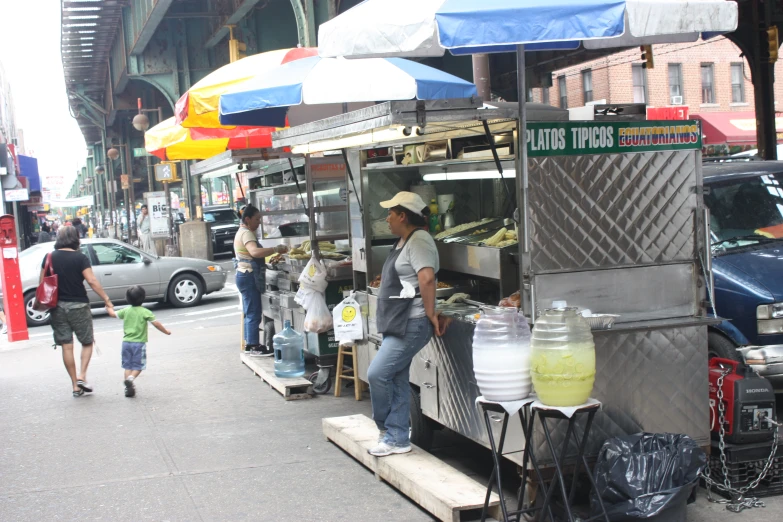 a small food stand with people walking on the sidewalk