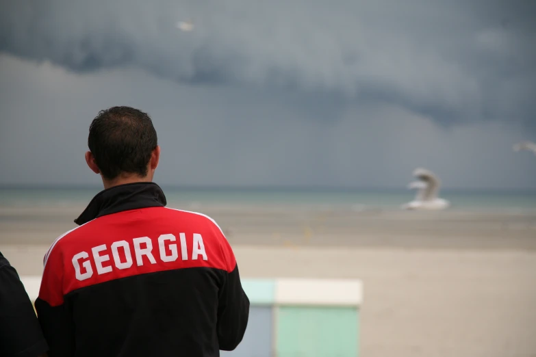 two men are looking at the ocean on a cloudy day