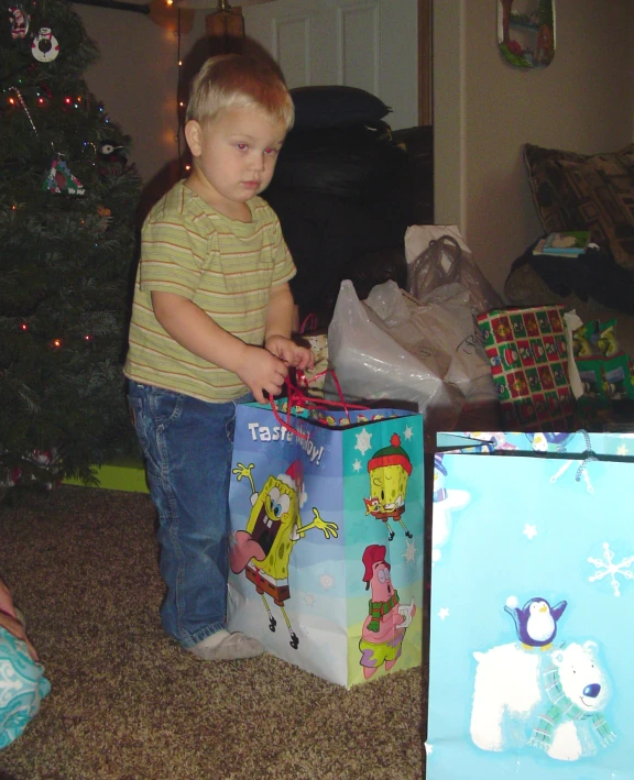 the boy is standing in front of the christmas gift bags