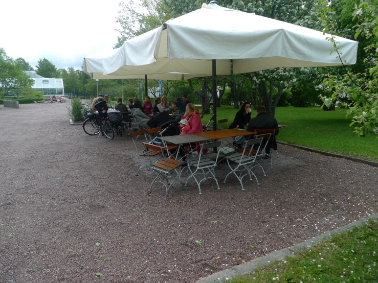 a group of people are sitting under a table outside