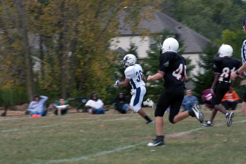 young football players running the ball on field