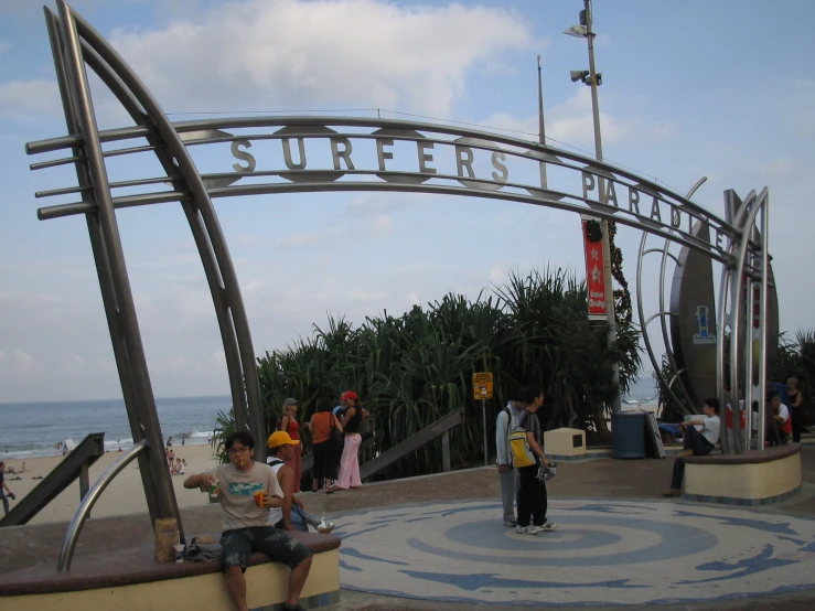 several people stand under an arched, metal sign