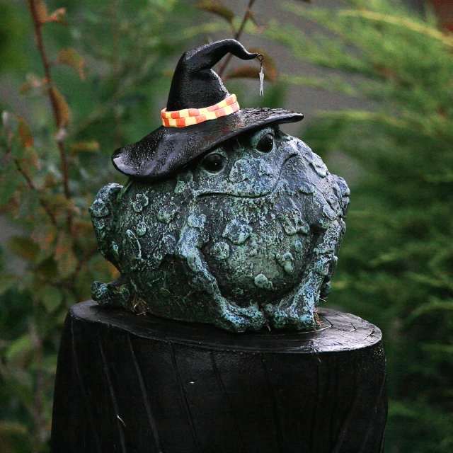 a statue wearing a witches hat with her head resting on a tree stump