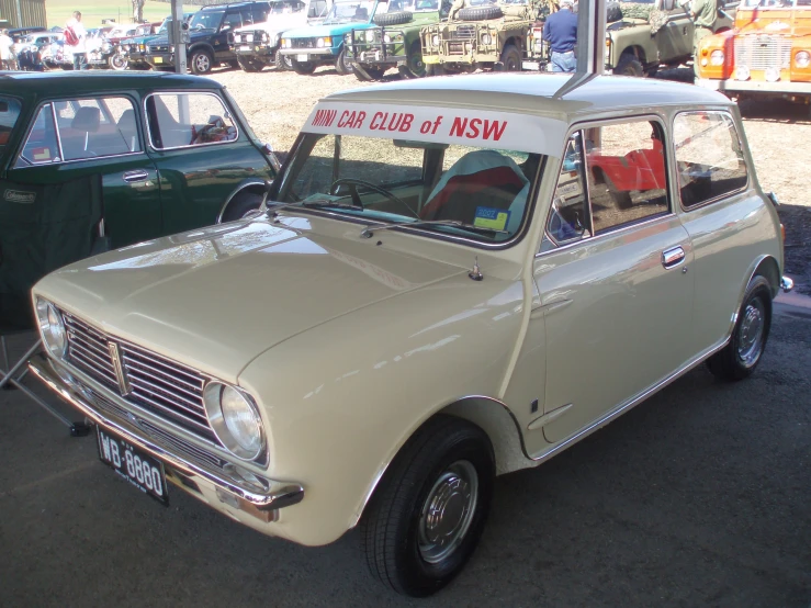 a tan and white car sitting next to other cars