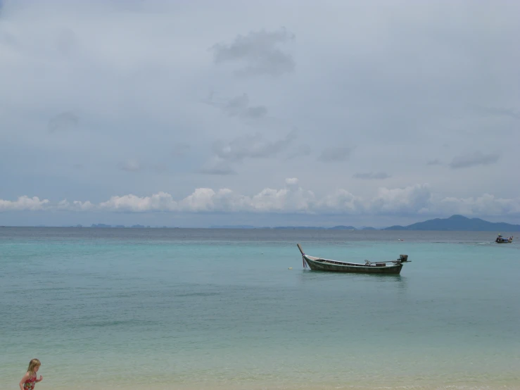 boat anchored on the sea with one person standing at a beach