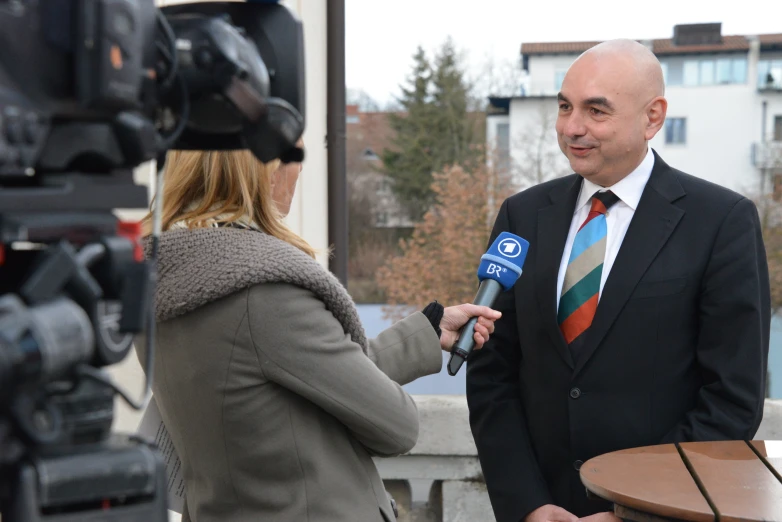 man is interviewed by a news reporter and is holding a microphone