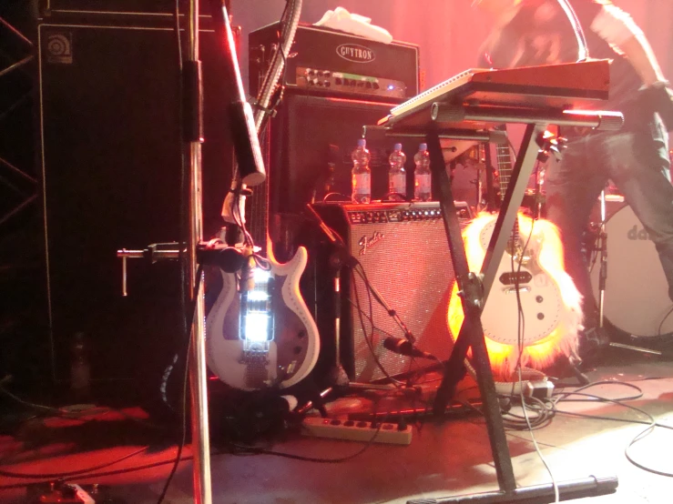 man standing on stage next to guitar and amp