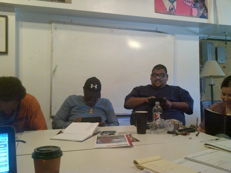 several people are sitting at a large table with their laptops