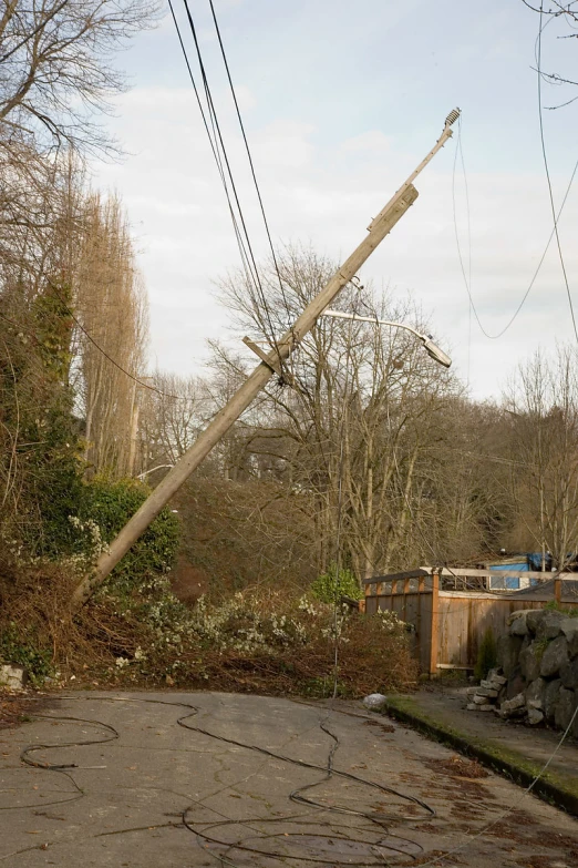 an electrical power pole leans toward the ground