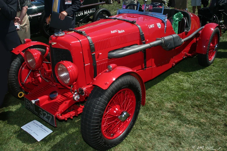 vintage cars are parked near some people on the grass