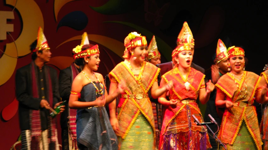 several young women wearing traditional dress stand on stage