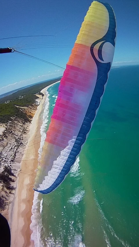 an aerial view of the beach and ocean with a parachute