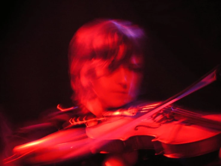 a person in a red light playing a violin