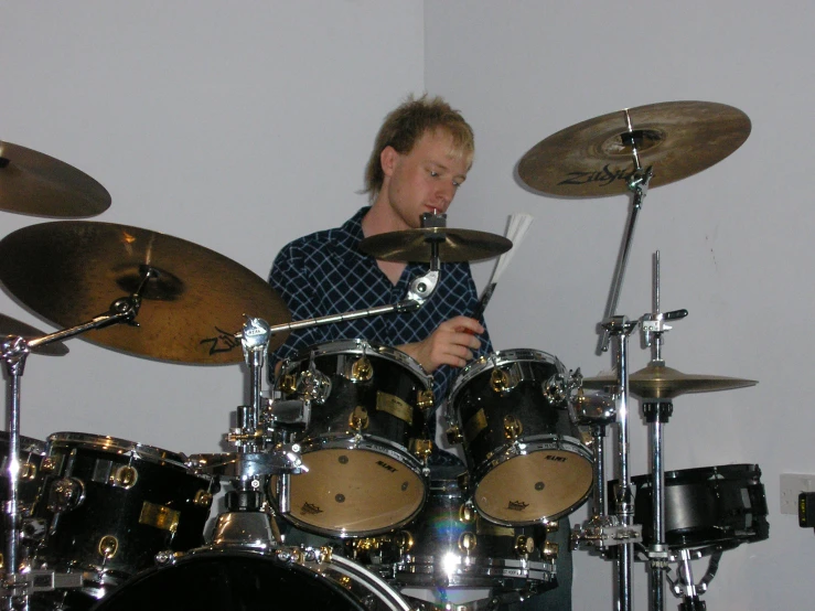 man playing drums with a white wall in the background