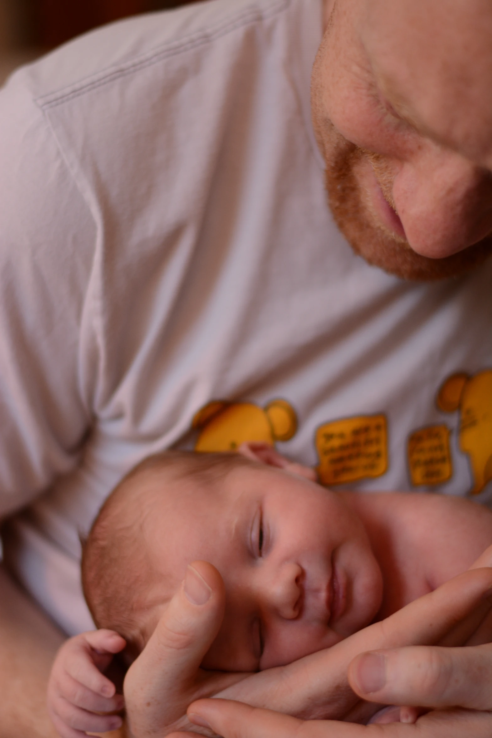 a man holding a newborn baby with orange speech bubbles on it