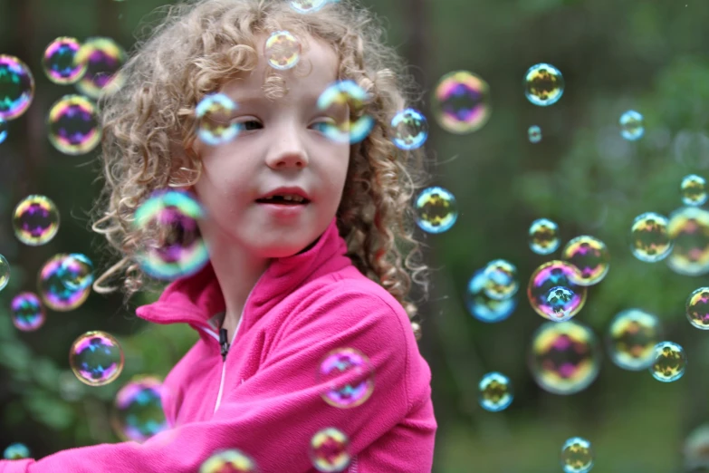 a little girl standing on top of a field with soap bubbles