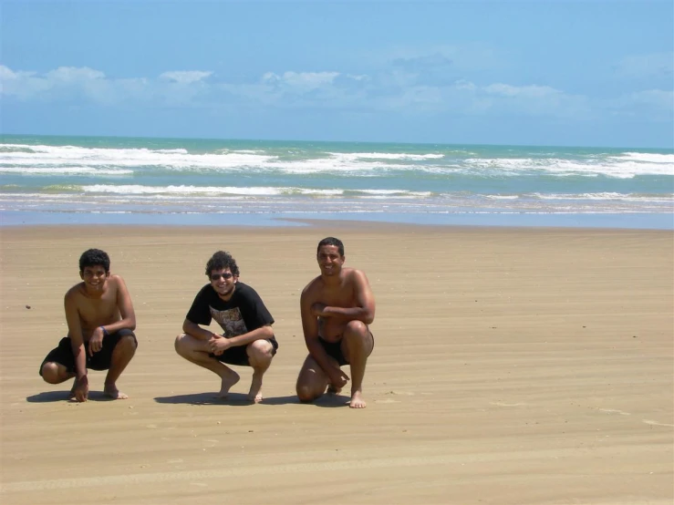 three people pose for a po on the beach