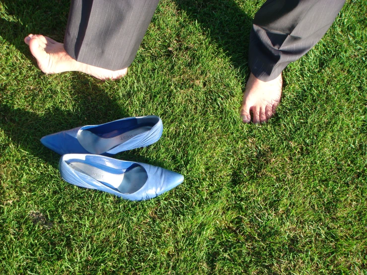 someone in blue slippers stands on a grass lawn