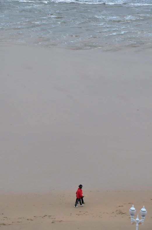 man walking in the sand near two fire hydrants