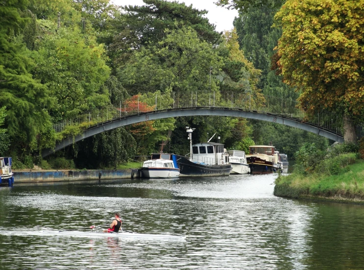 several boats travel down a river under a bridge