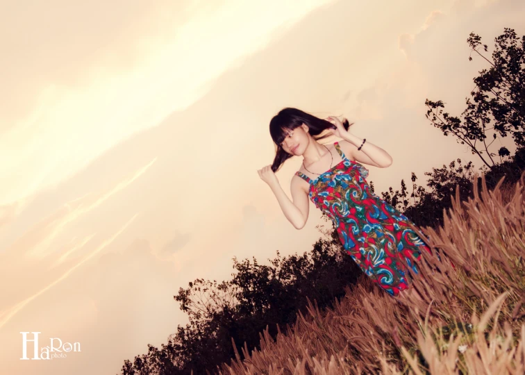 a woman is posing in tall grass while wearing a red dress