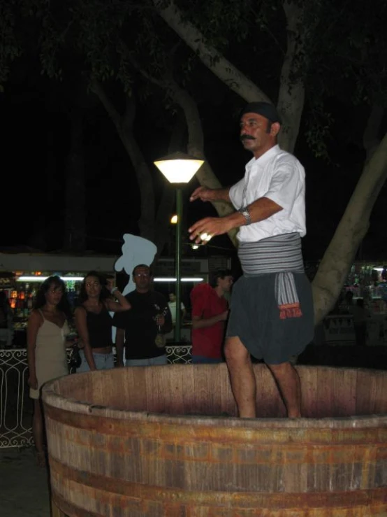 a man smoking a cigarette while sitting in front of a barrel