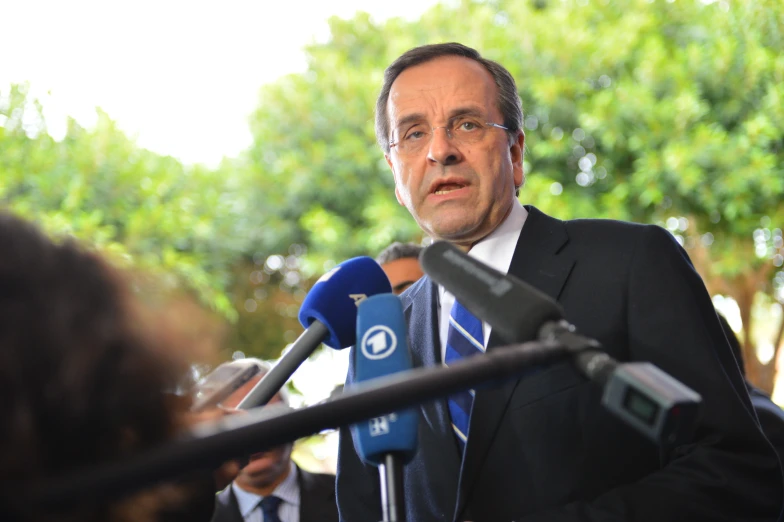 a man in suit and tie standing next to microphones