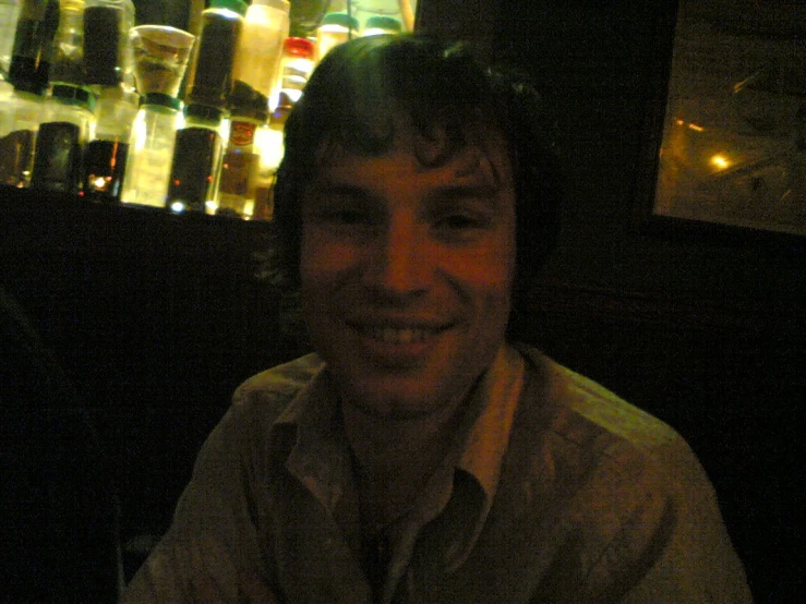 a man in a restaurant with wine bottles behind him