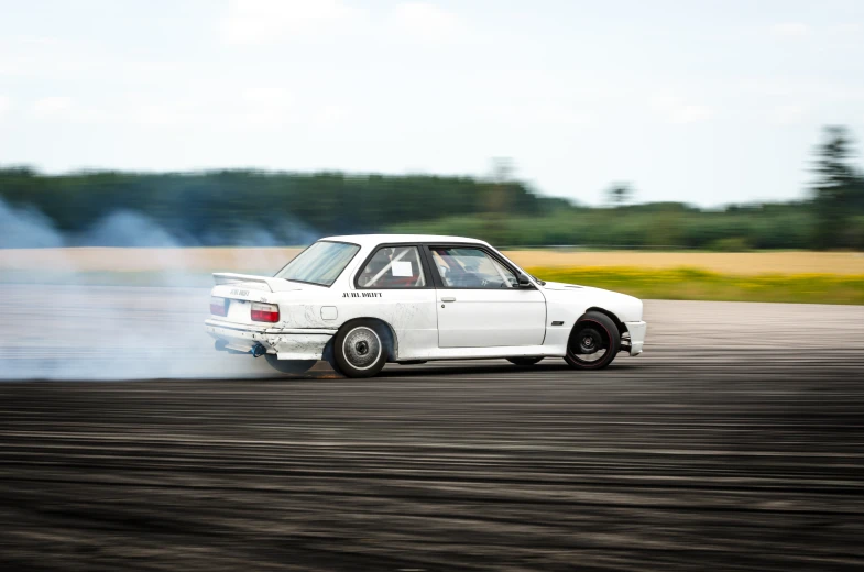 a white race car with it's wheels spinning as smoke from it comes out of the window
