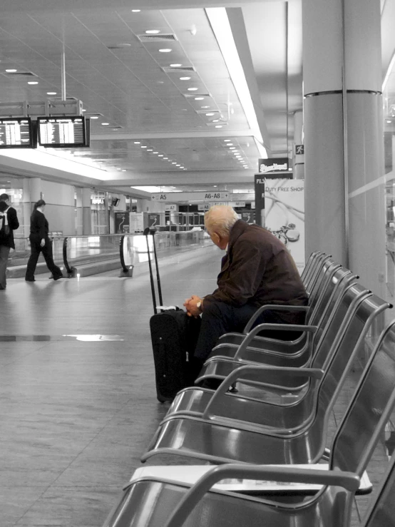 an old man is sitting at a terminal with his suitcase