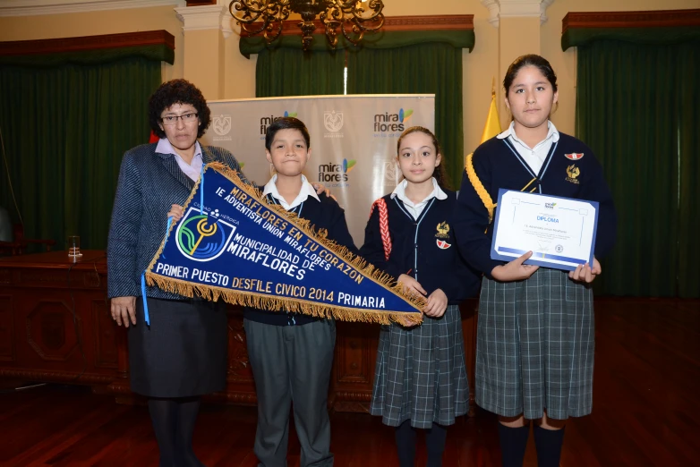 four students and two teachers stand in a room holding signs