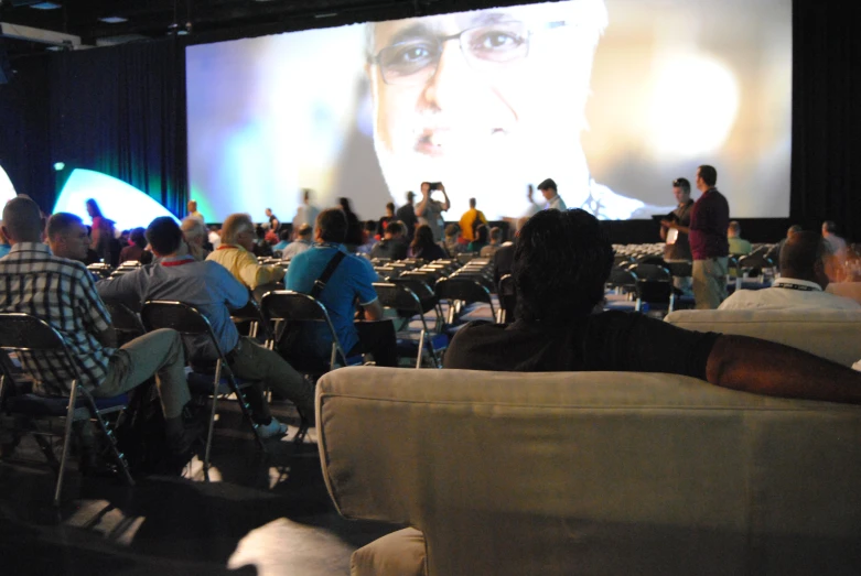 a group of people are in chairs around a big screen
